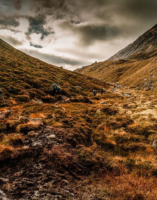 Hiker crossing Hikers crossing a mountain valley in the Cairngorms National Park, Scottish Highlands.