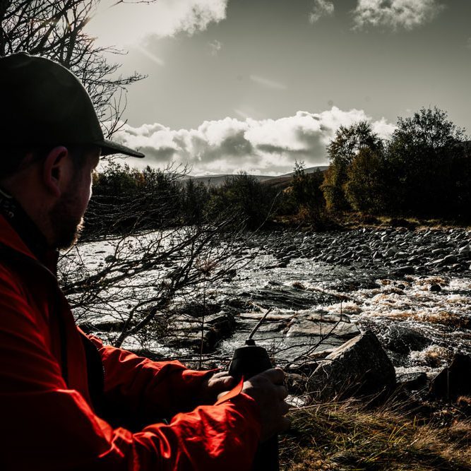 Cairngorm break Hiker taking a break beside a mountain river in the Cairngorms National Park, Scottish Highlands.