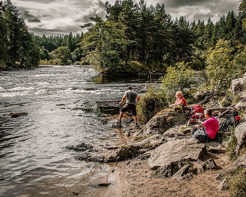 Hikers taking a break Hikers taking a break beside the River Spey in Speyside, Scotland.
